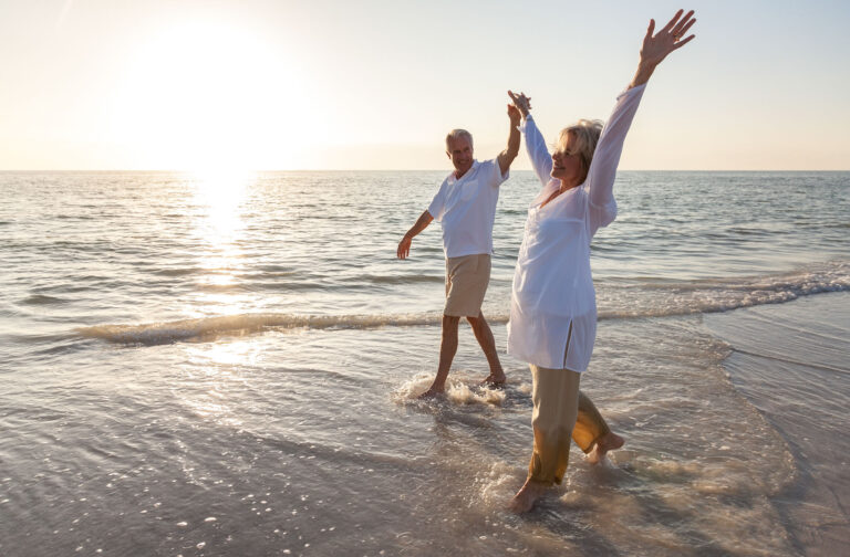 happy senior couple holding hands sunset sunrise beach